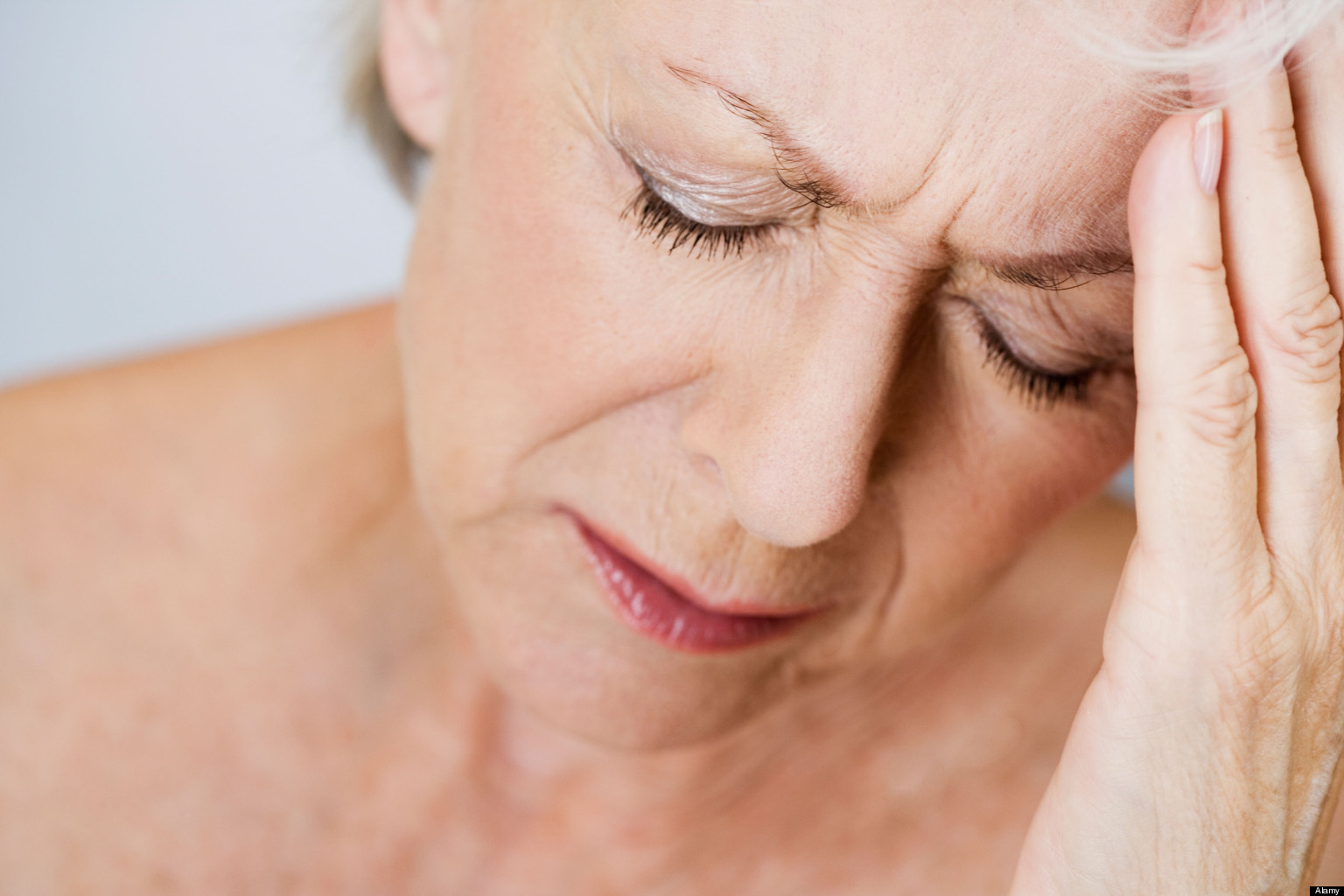 A senior woman with a headache, touching her forehead